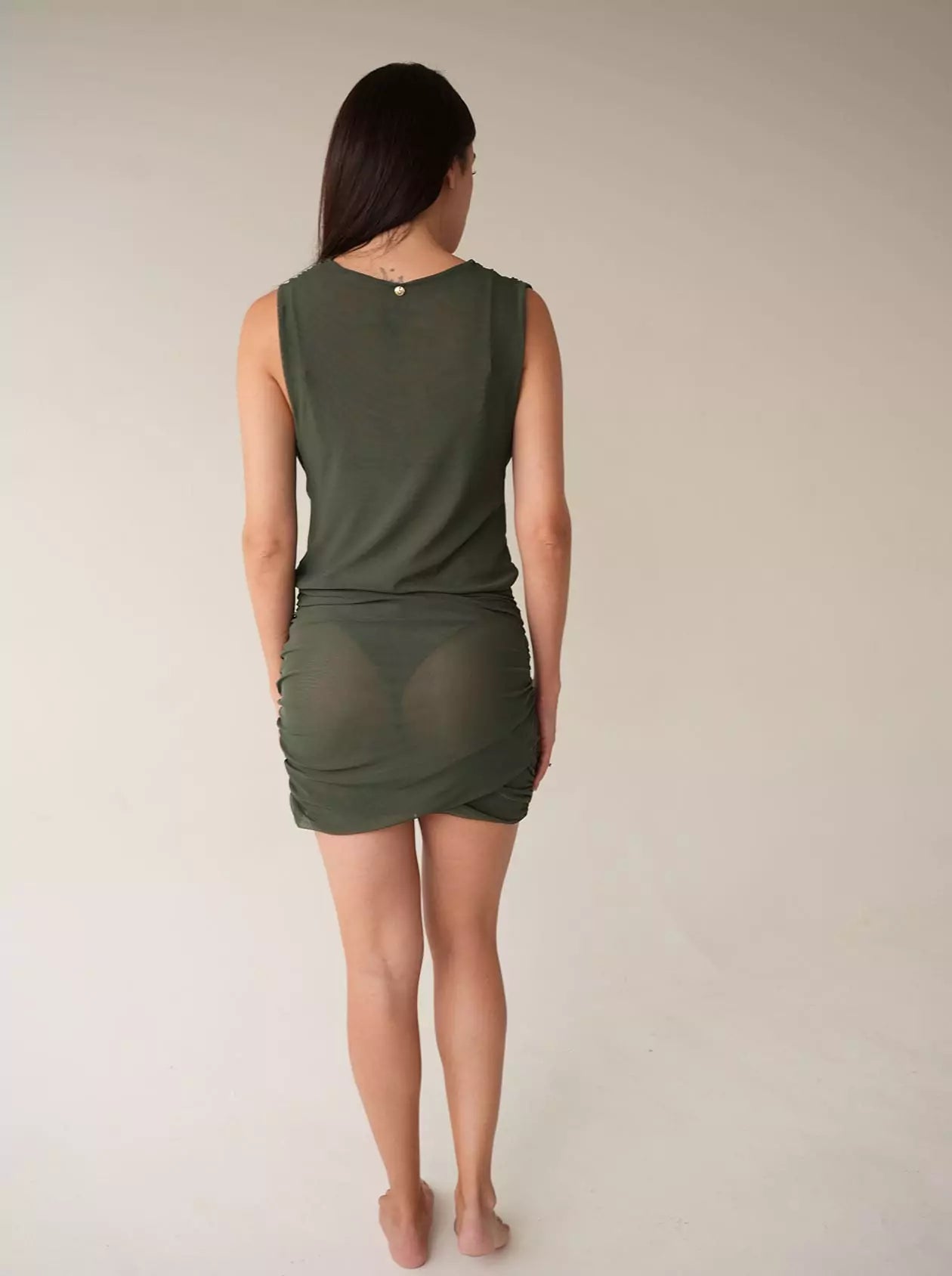 Back view of sheer ruched mesh mini dress in green with open back