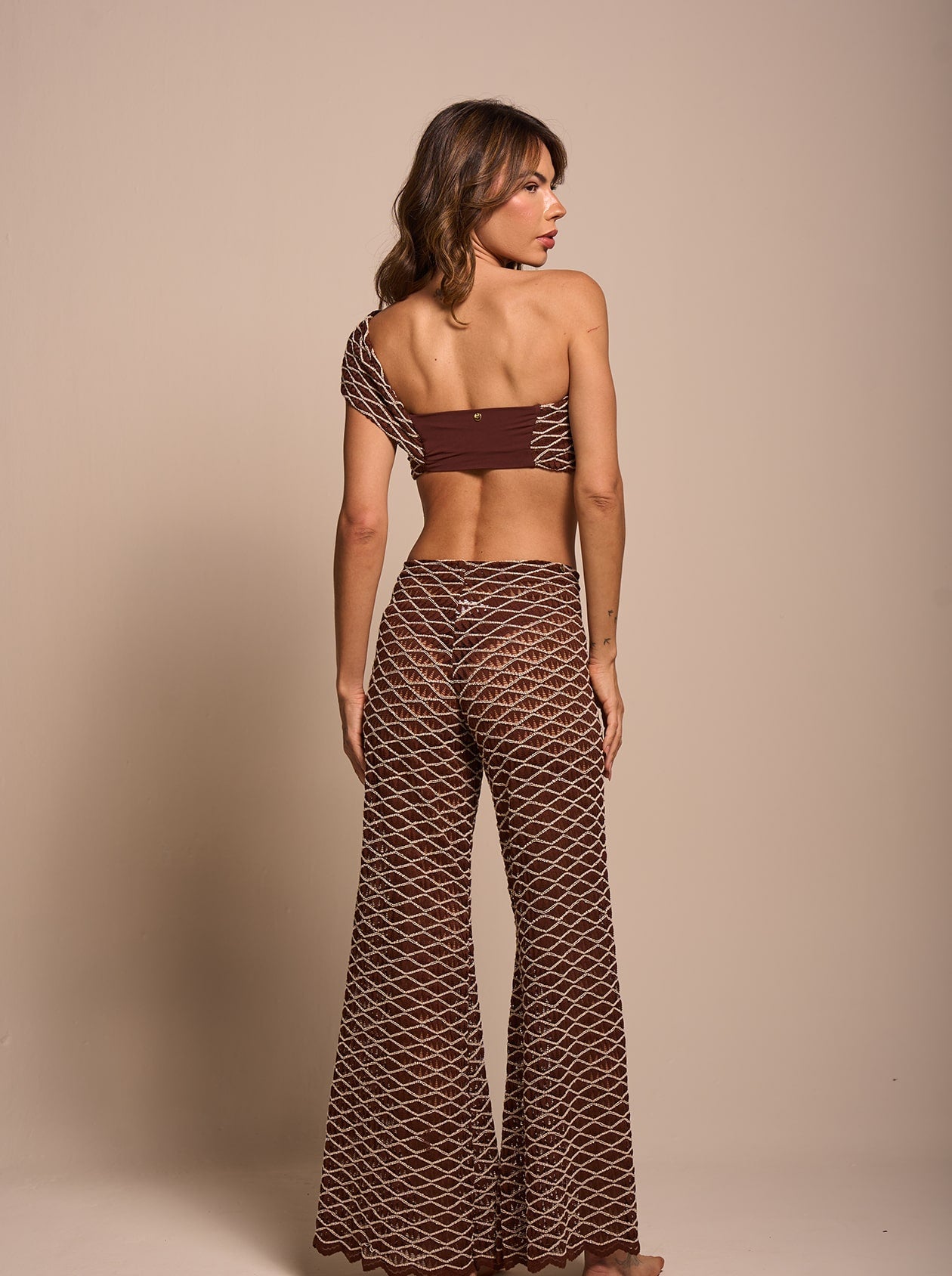 Back view of the Chocolate Shimmer Flare Beach Pants showing the high-rise fit, open-knit shimmer fabric and flared legs.
