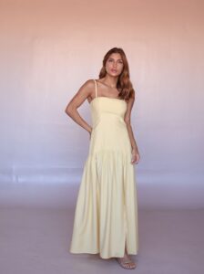 Woman wearing the Soleil Linen Blend Maxi Dress in butter yellow with adjustable straps and a flowing maxi silhouette.
