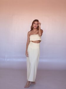 Model wearing the Lumière Linen Set in Butter Cream featuring a strapless crop top and flowing maxi skirt.