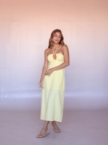 Model wearing the Solea Halter Midi Dress in Butter Yellow with a gathered bandeau neckline and front keyhole detail.