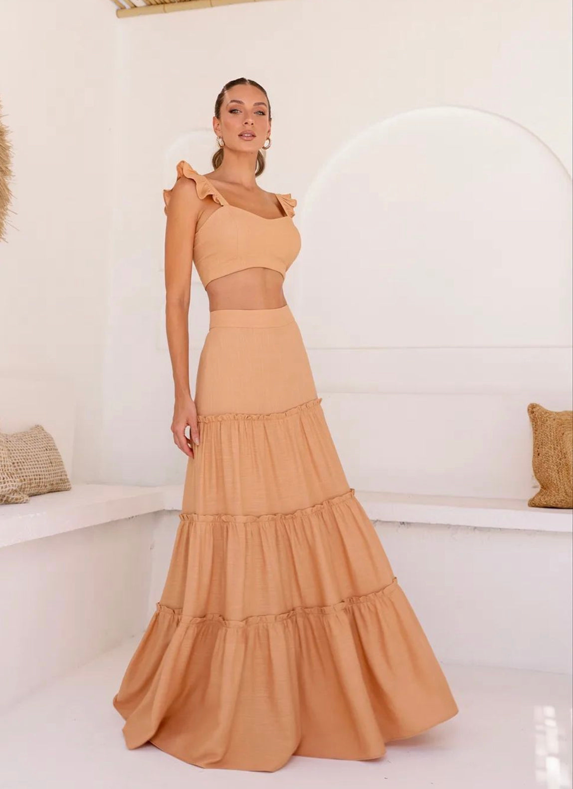 Model wearing beige two-piece set with high-waisted tiered maxi skirt and cropped top, ideal for resortwear.