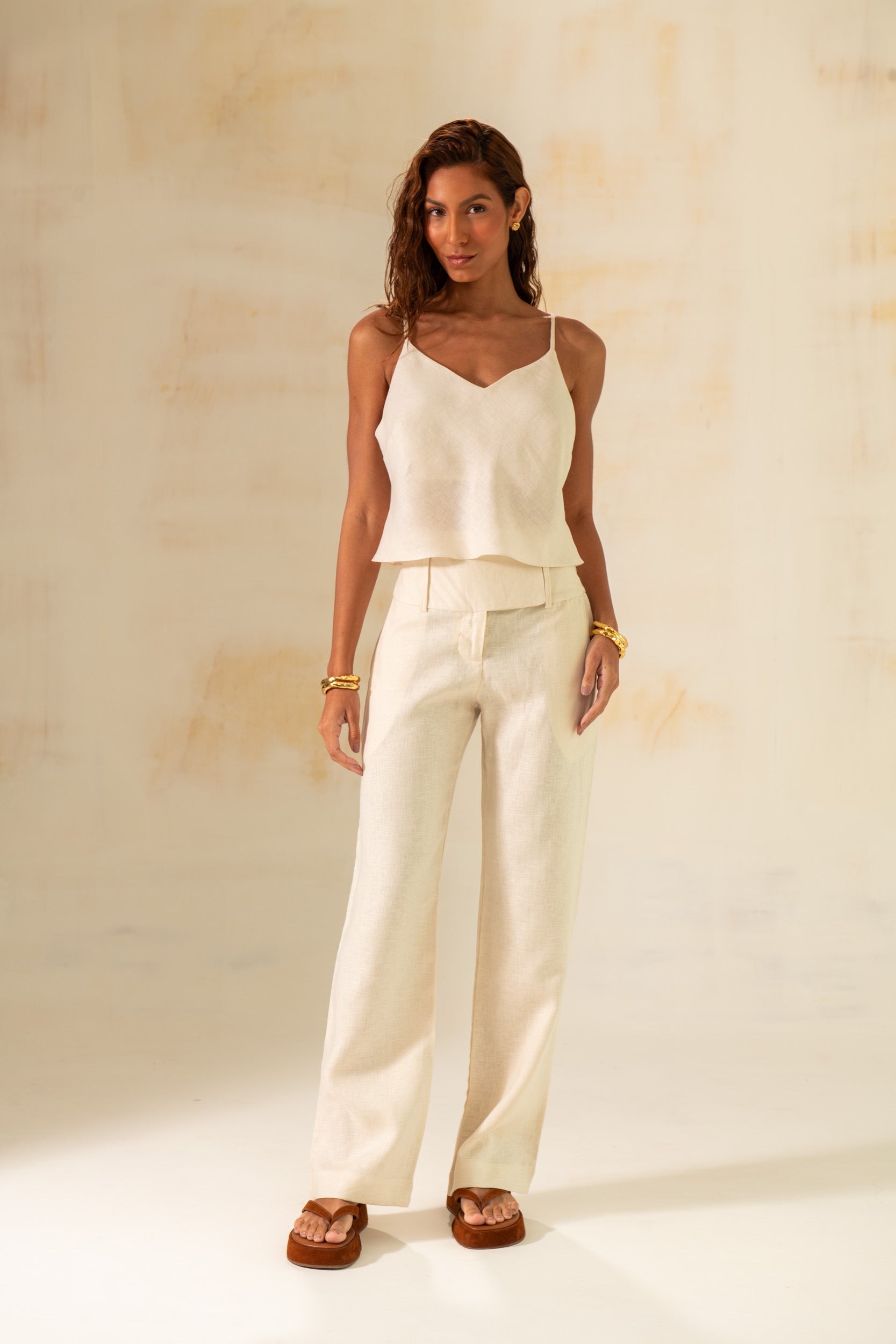 Model wearing Amazônia B2R linen pants in light green and off white with high waist and straight-leg fit. Styled in natural light for a tropical-chic resort look.