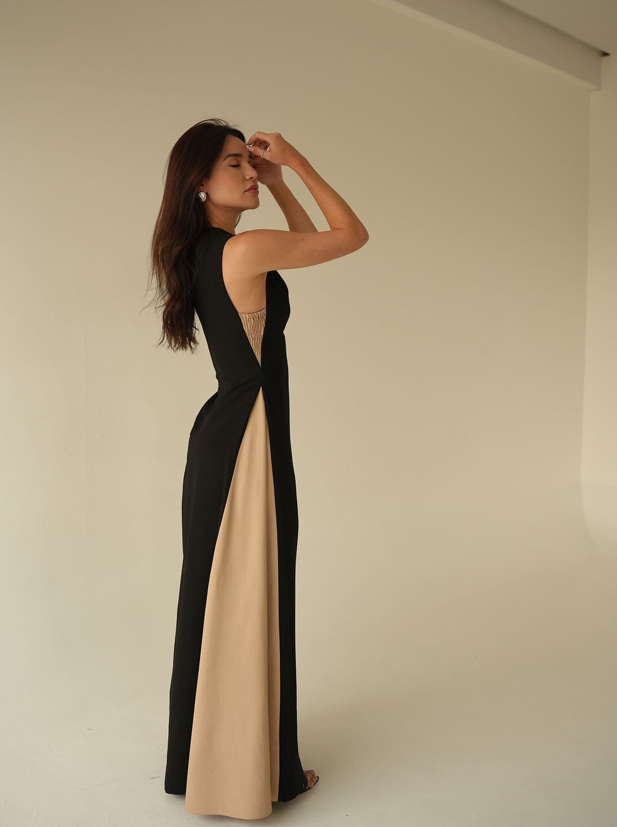 Model wearing long bicolor black and sand dress from Amazônia B2R in a minimalist studio setup, perfect for upscale resort occasions