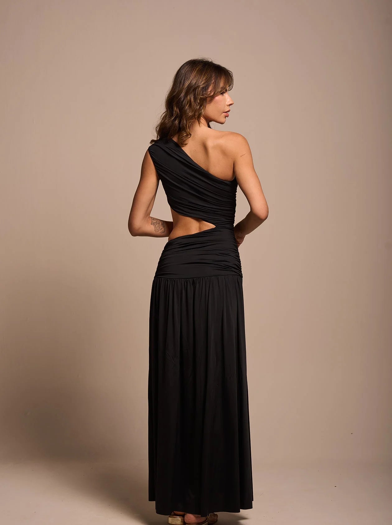 Full-body front view of Black draped dress showing side slit and sculpted silhouette; chic evening style.