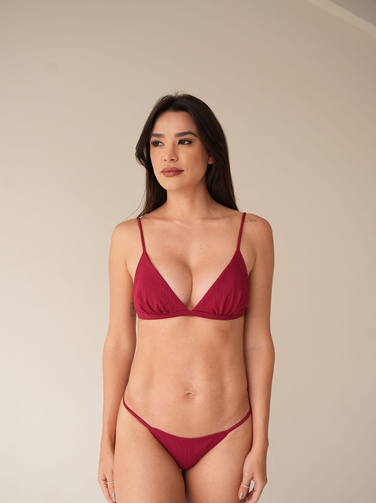 Model in burgundy triangle bikini with bronze bottom and textured finish, front view