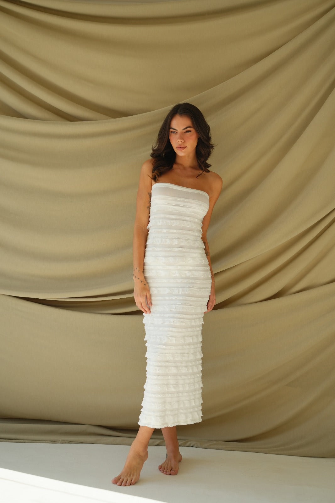 Model wearing off-white textured convertible dress with horizontal ruffle details – can be styled as skirt or strapless dress with inner lining, ideal for beach vacations and resortwear