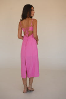 Person wearing a pink dress standing on a plain background